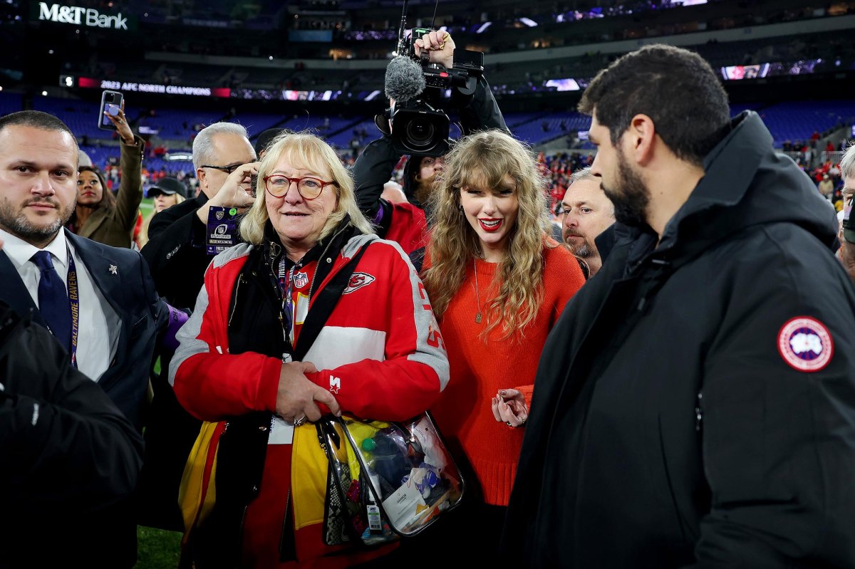 Taylor Swift is seen here standing on the field in the middle of a crown with Travis Kelce's mom.